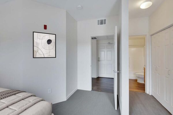 Trocadero apartment bedroom with plush bed, framed artwork, and living room door.