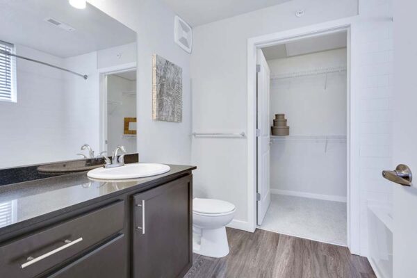 Monaco Row apartment bathroom with wood style floor, dark counters, and tiled shower tub.