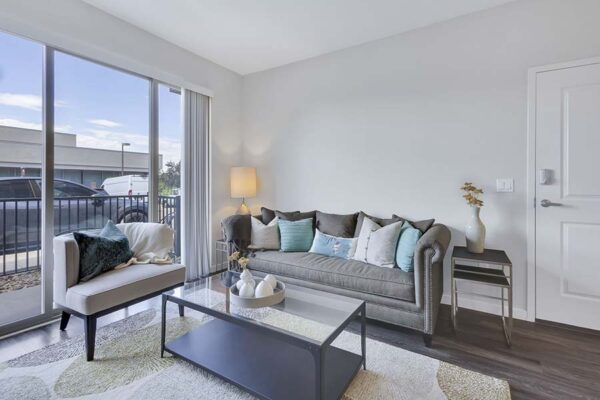 Monaco Row apartment living room with plush seating, elegant decor, and balcony door.