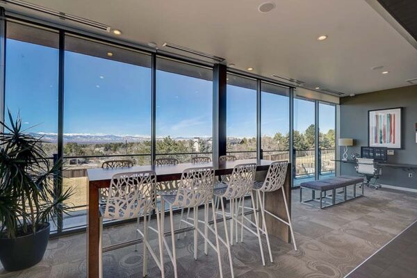 Monaco Row clubhouse lounge with tables and chairs overlooking front range mountains.