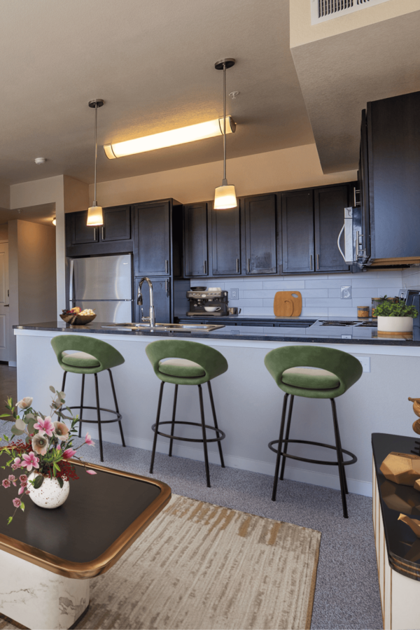green bar stools outside the kitchen counter with large kitchen and dark wood cabinets
