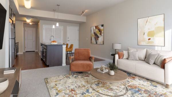 spacious living room with couch and accent chair with view into kitchen