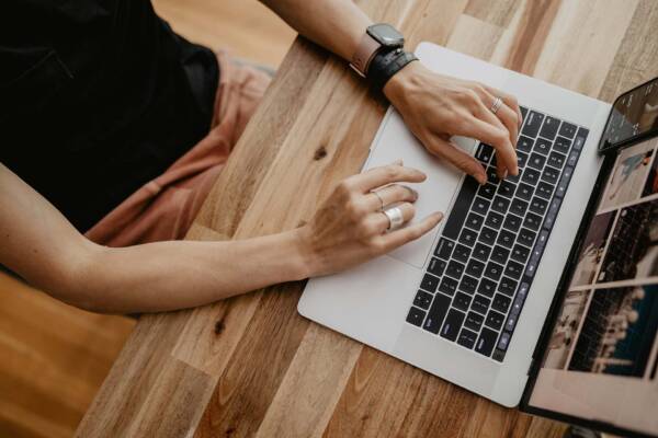 Person at wood desk working on laptop computer.