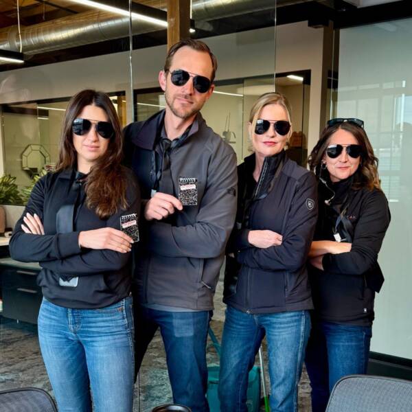 team of four people posing with arms crosses and glasses on