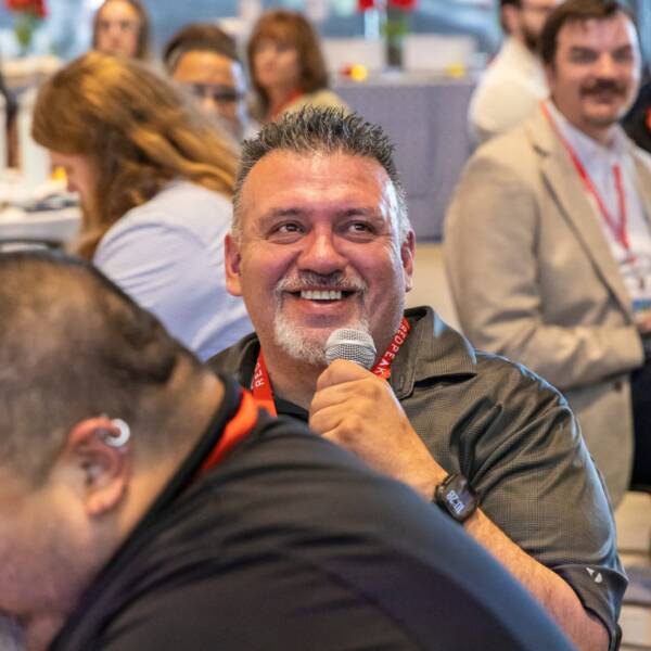man holding microphone smiling into crowd