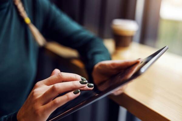 Person holding a tablet at a coffee shop.