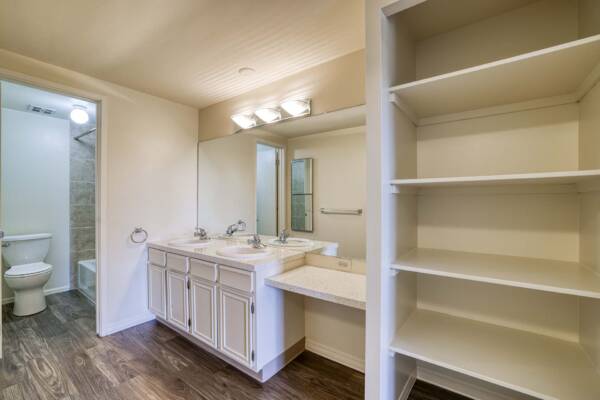 The Manchester apartment bathroom with wood style floor and built in shelves.