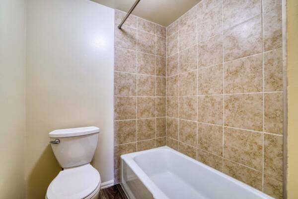 The Manchester apartment bathroom with wood style floor and tiled shower tub.