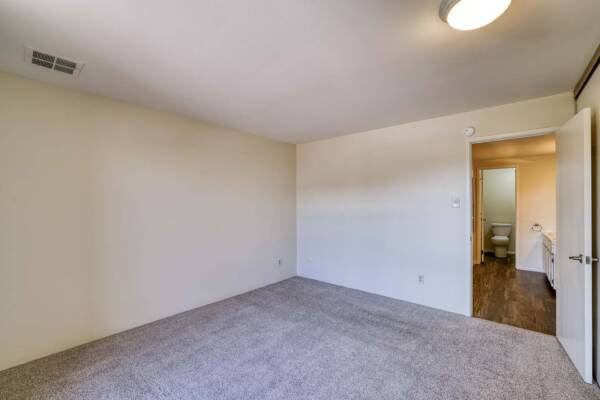 The Manchester apartment bedroom with carpet and bathroom door.