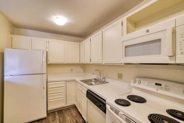 The Manchester apartment kitchen with wood style floor and white appliances.