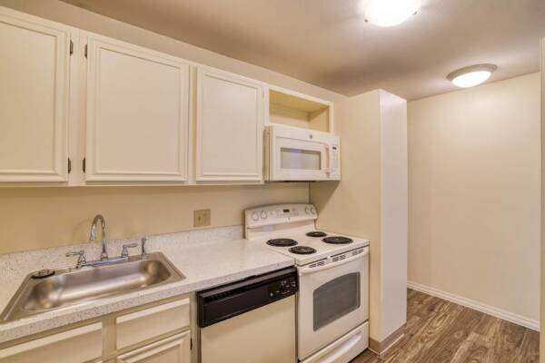 The Manchester apartment kitchen with wood style floor and white appliances.